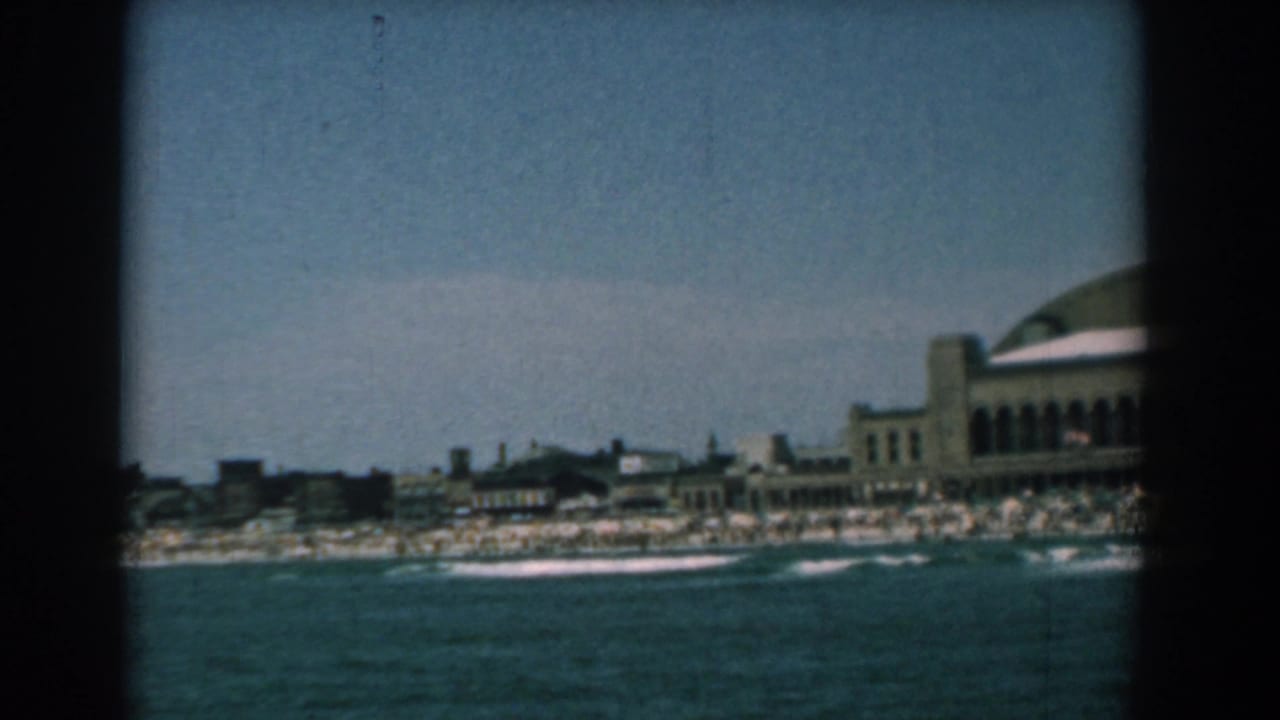 Yorktown, Virginia shoreline in 1958, filmed from across the water with surf, beach crowds, low buildings, and a curved-roof resort structure.