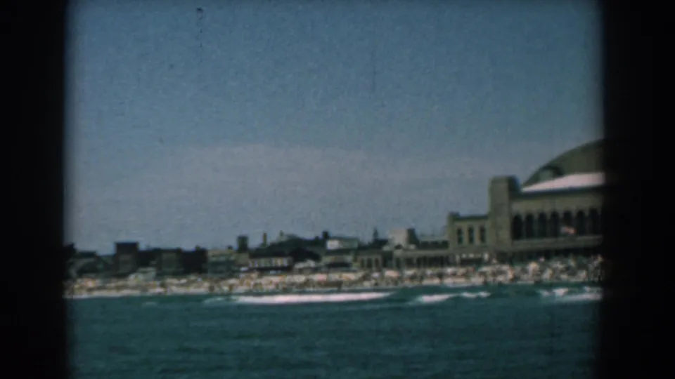 Yorktown, Virginia shoreline in 1958, filmed from across the water with surf, beach crowds, low buildings, and a curved-roof resort structure.