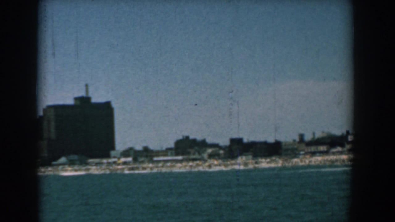 Waterfront skyline with a prominent dark high-rise and sandy shore.