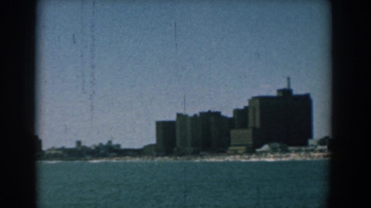Distant Yorktown shoreline view with large grey buildings, low beach area, and open water in the foreground.