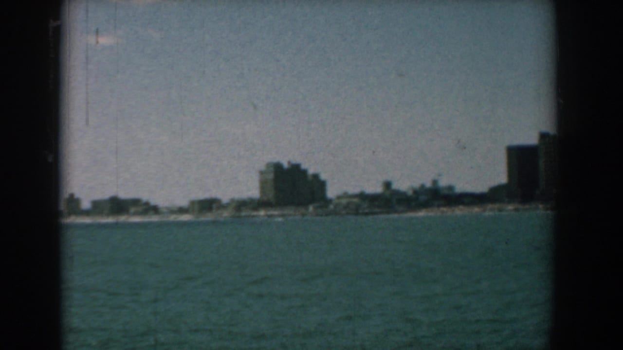 Coastal skyline across the water with a tall dark building at the right edge.