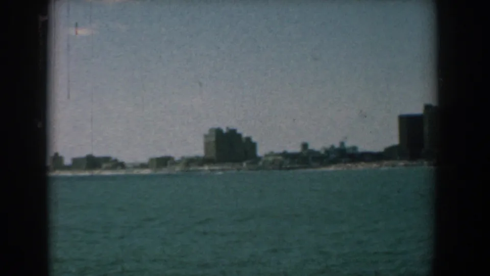 A Yorktown-area waterfront skyline appears across the water in faded 8mm color, with larger buildings toward the right.