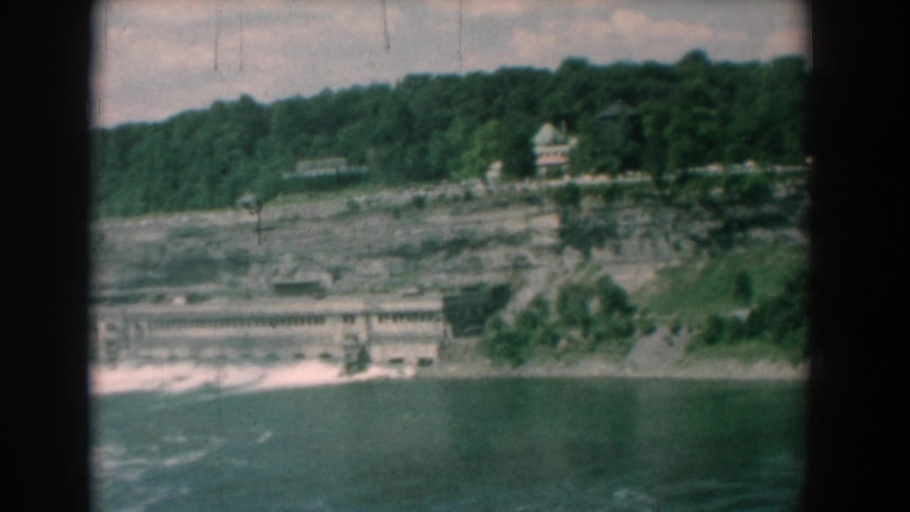 River and low shoreline structure beneath a tree-covered ridge.