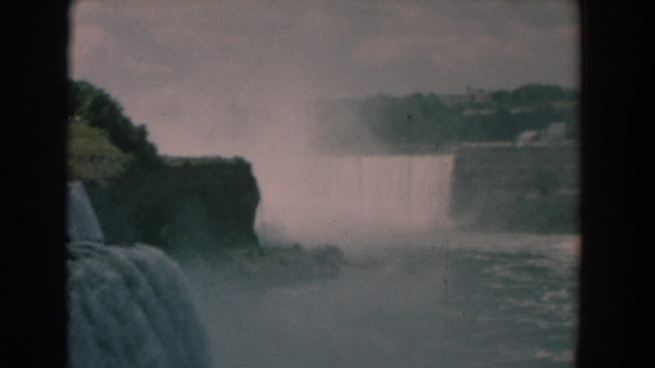 Wide view of waterfalls, mist, river water, and dark central frame border.