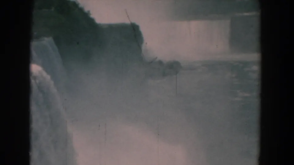 1958 8mm home-movie frame showing a large waterfall, mist, cliff edge, and turbulent water below.