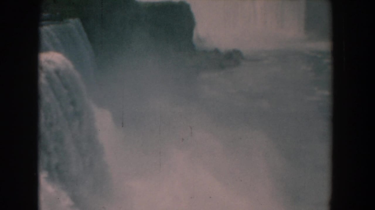 Misty waterfall with broad water surface and dark film borders.