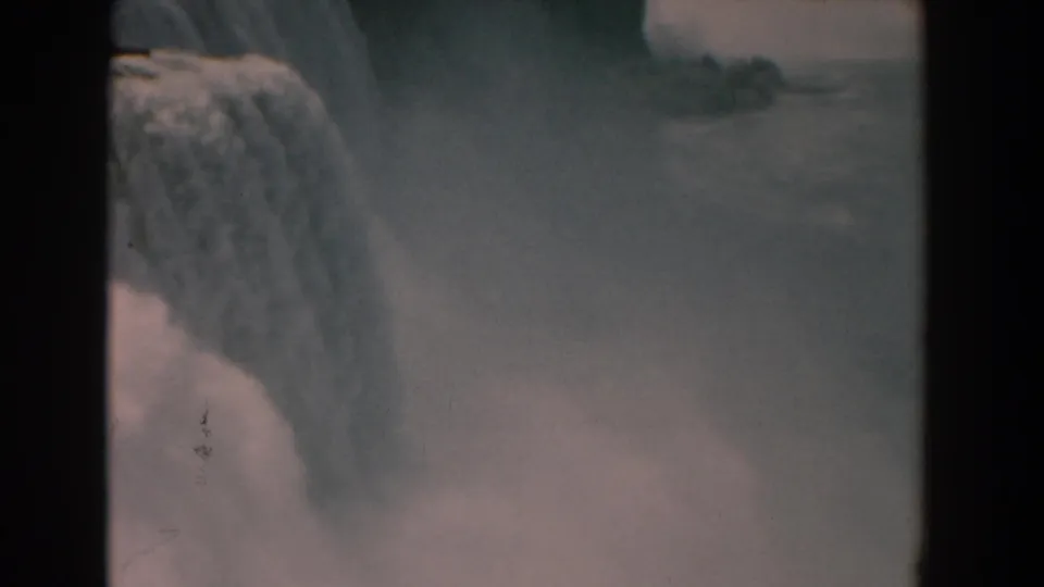 1950s 8mm frame showing American Falls at Niagara Falls with a broad curtain of water and mist rising below.