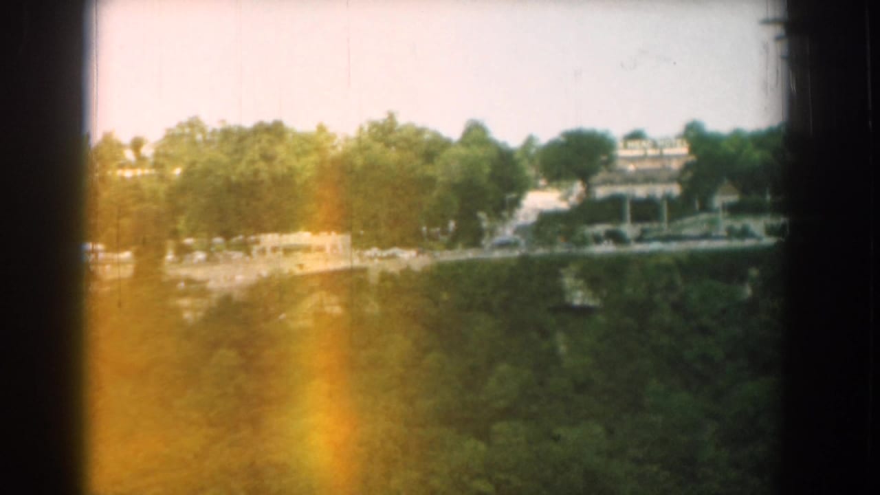 Wooded overlook with distant buildings and dark 8mm frame borders.