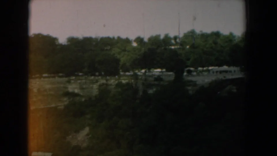1958 Yorktown, Virginia 8mm frame showing a darker tree-lined river view with warm orange light leak along the lower left edge.