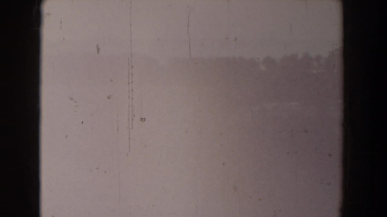Mostly blank faded film frame with scratches and faint landscape detail.