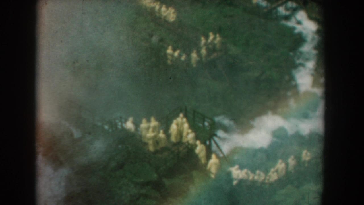 1958 Yorktown, Virginia 8mm frame showing people in yellow clothing on a wooded platform, seen from a distant home-movie viewpoint.