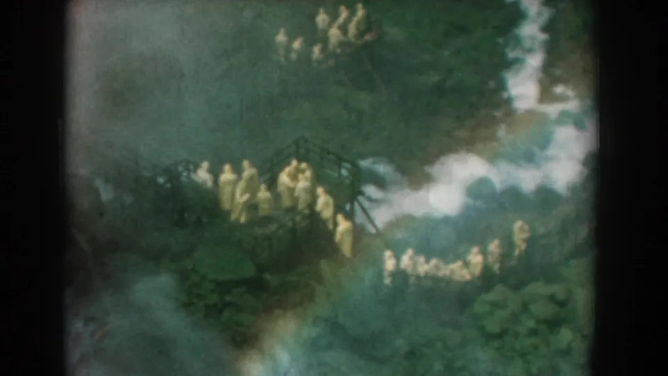 The Yorktown home-movie frame shows a cluster of people in yellow garments on a raised wooden structure in a wooded setting.