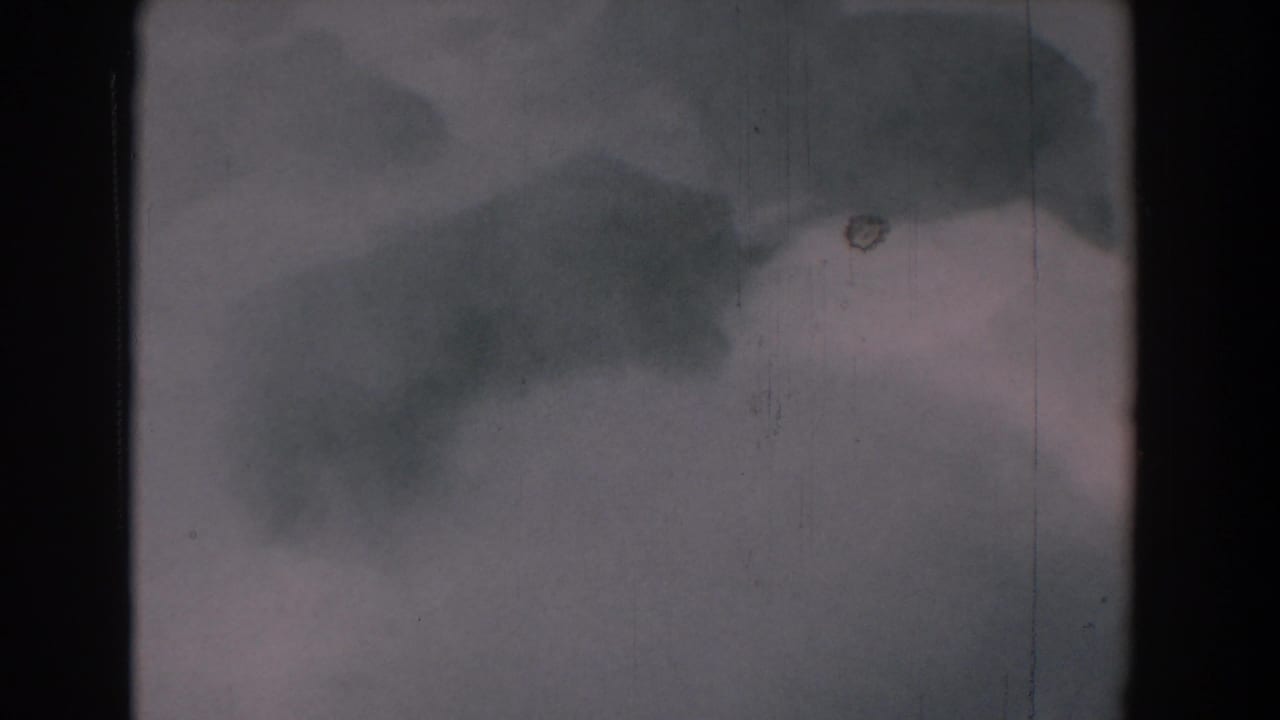 Misty water or spray with dark soft-edged shapes and visible film scratches.