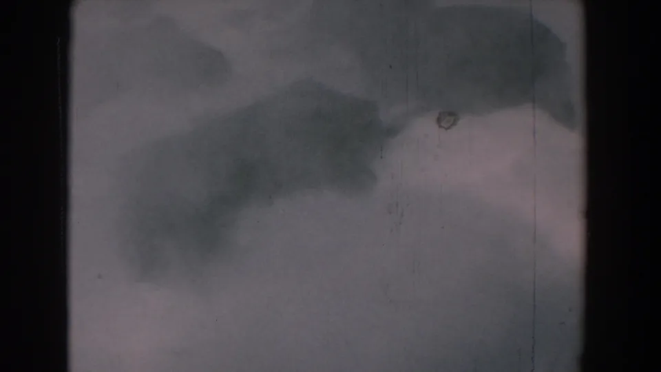 1958 8mm frame from Yorktown, Virginia, showing pale mist over water with dark soft forms, dust, scratches, and rounded film edges.