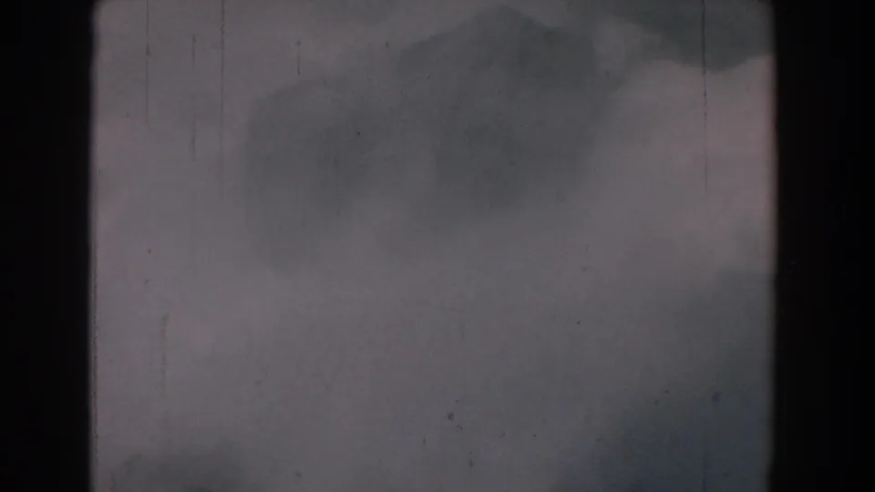 Yorktown-area 1958 home-movie frame with misty gray water or haze, faint dark forms, film grain, scratches, and edge vignetting.