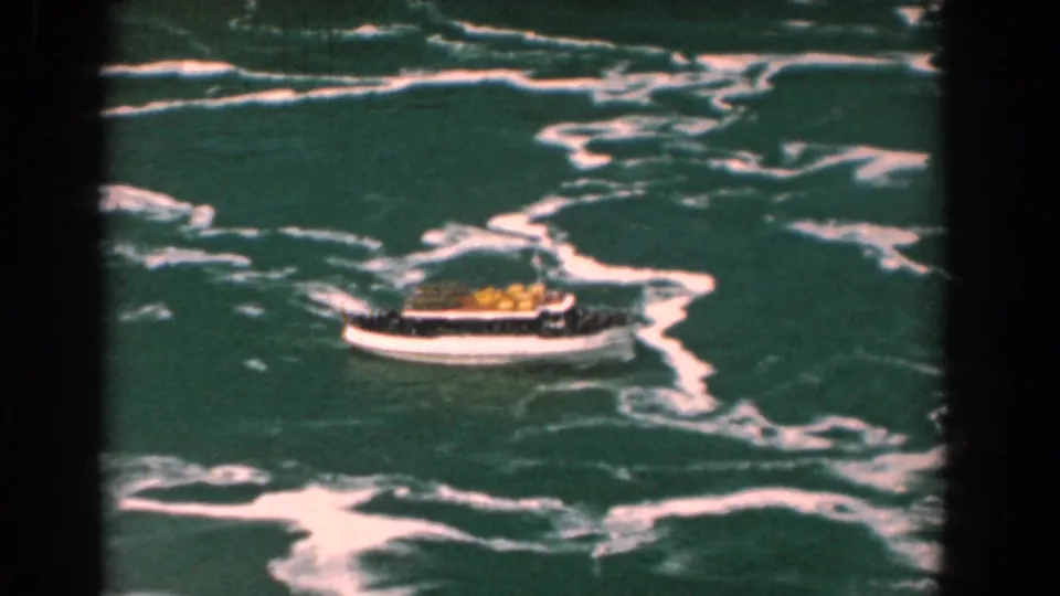 Small white tour boat with a yellow canopy appears on churning green water in Yorktown, Virginia footage from 1958.