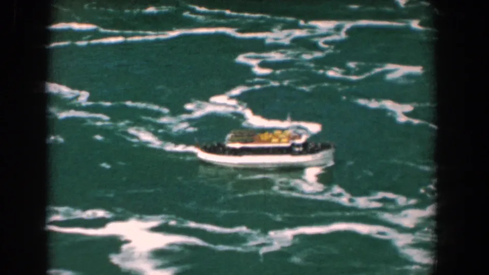Final frame shows the canopy-topped boat at right, moving through foamy Yorktown water on grainy 8mm film.