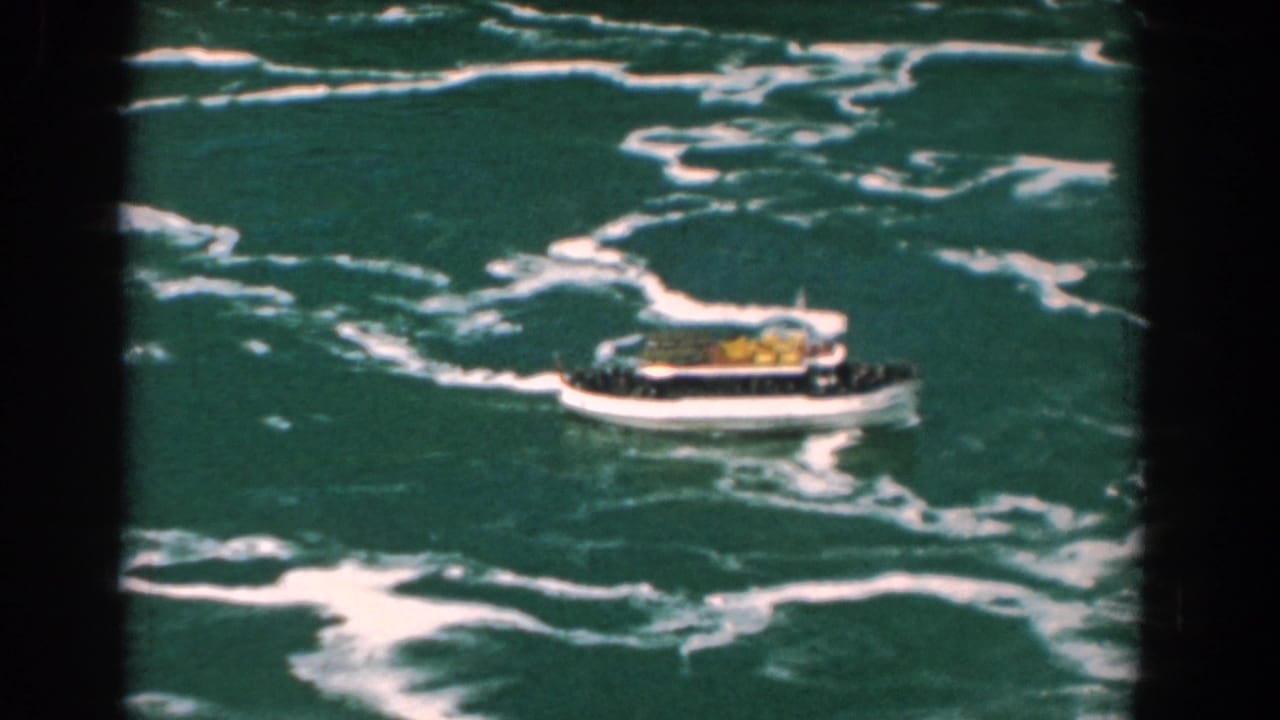 Small tour boat moving through foaming green water seen from above.