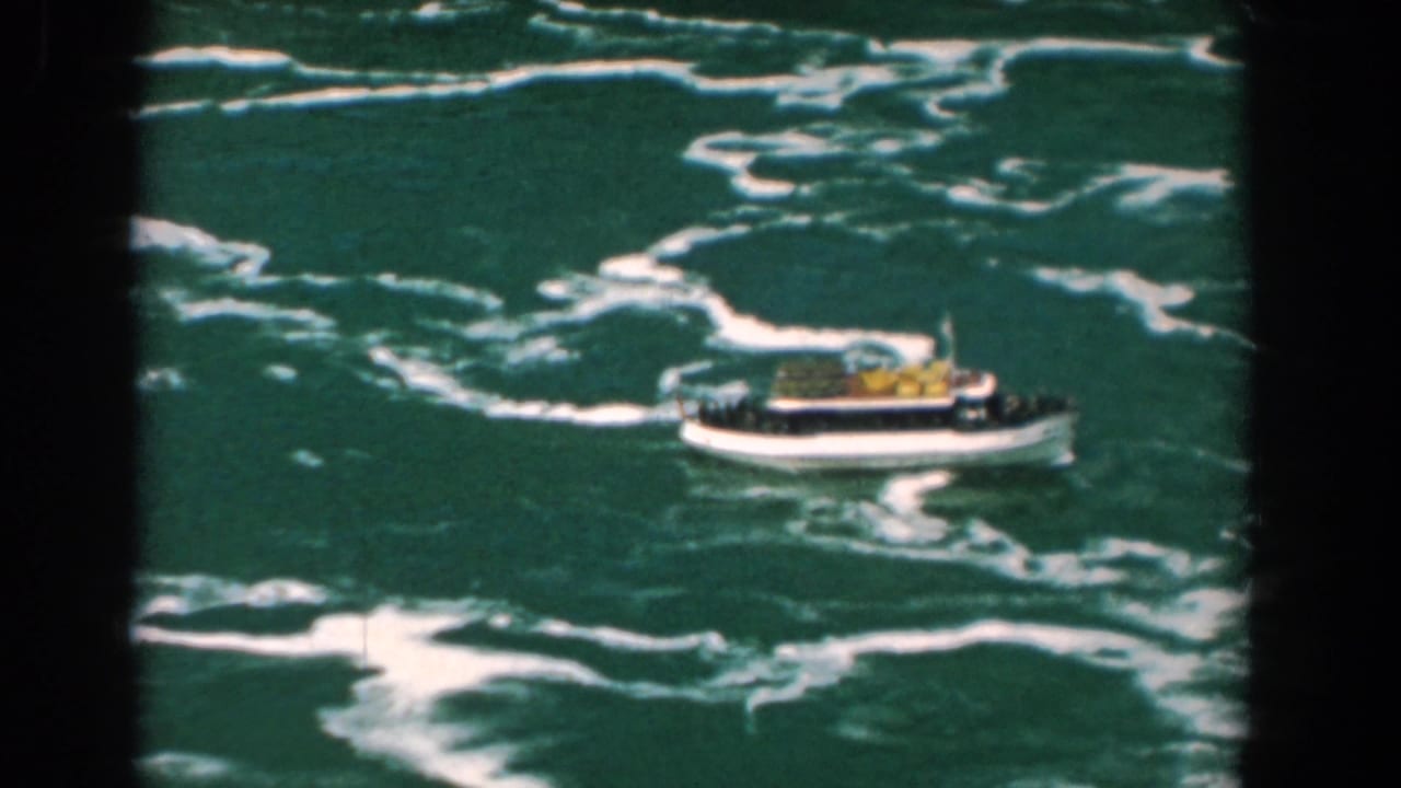 Tour boat on churning water with white foam viewed from above.
