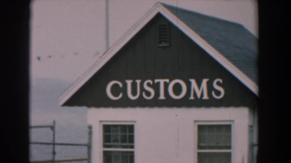 Yorktown, Virginia 1958 frame of the CUSTOMS sign on a small white building, with roofline, windows, railing, and water beyond.