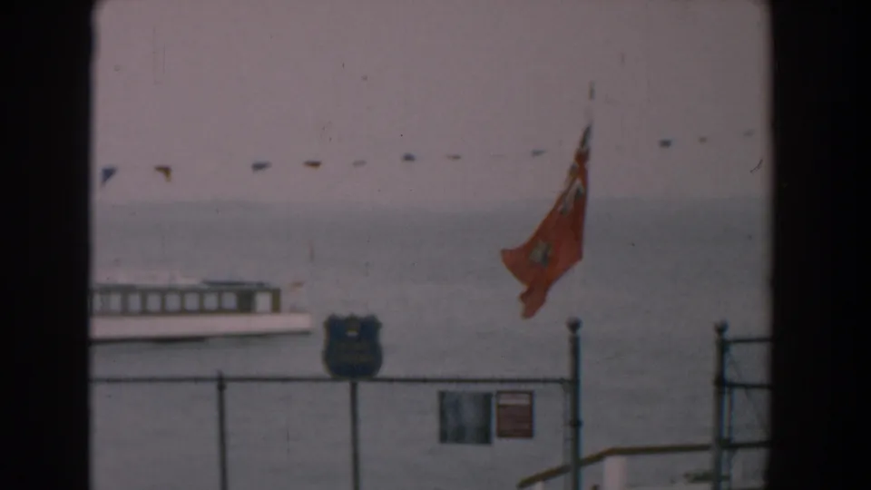 1958 Yorktown waterfront view with a ferry, red Ontario flag, bunting, fence, and shield-shaped shoreline sign.