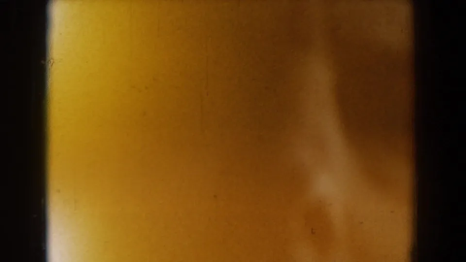1958 Yorktown 8mm frame with a soft, obscured face-like form behind dark film-strip divisions and warm yellow exposure.