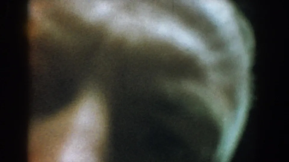 Soft, out-of-focus opening frame from 1958 8mm footage, showing indistinct green-brown forms and dark frame edges.