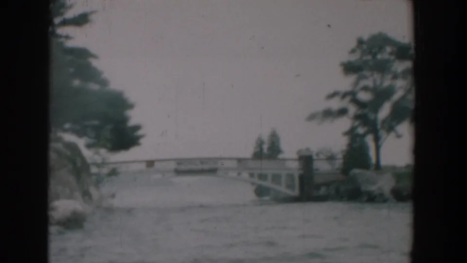 The Yorktown river scene holds on the bridge and landscaped bank, with soft 8mm color and visible film scratches.
