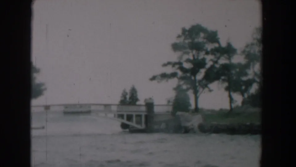 A 1958 Yorktown 8mm frame shows the bridge receding to the left with trees and shoreline rocks along the river.