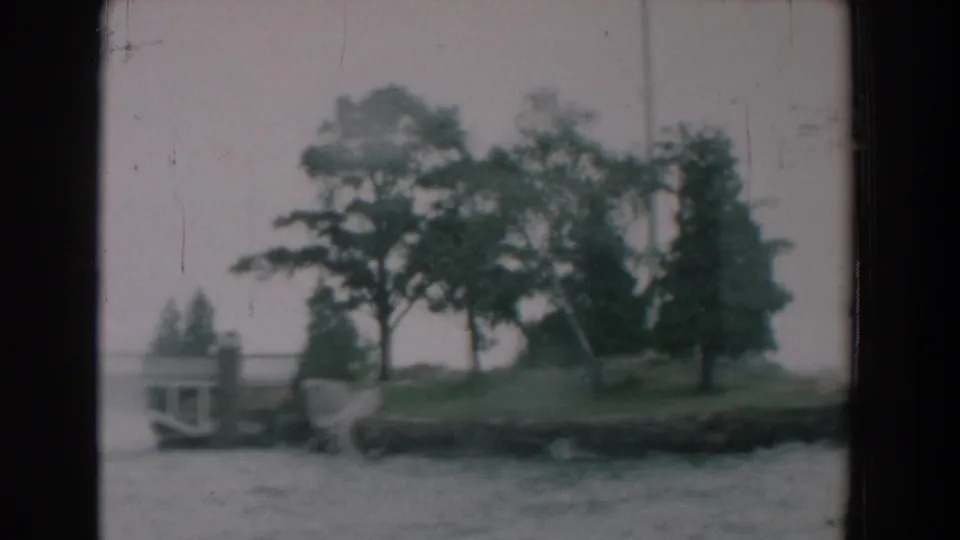 1958 8mm view from a boat toward a small wooded shoreline in Yorktown, Virginia, with water in the foreground.