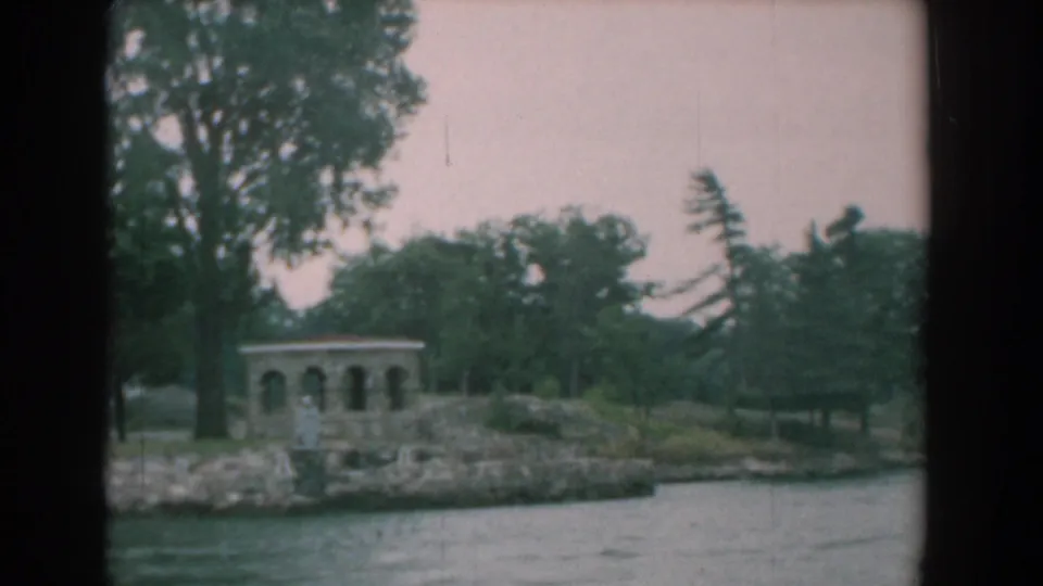 Yorktown, Virginia shoreline scene from 1958 with a small arched gazebo, trees, stone edge, and river water.