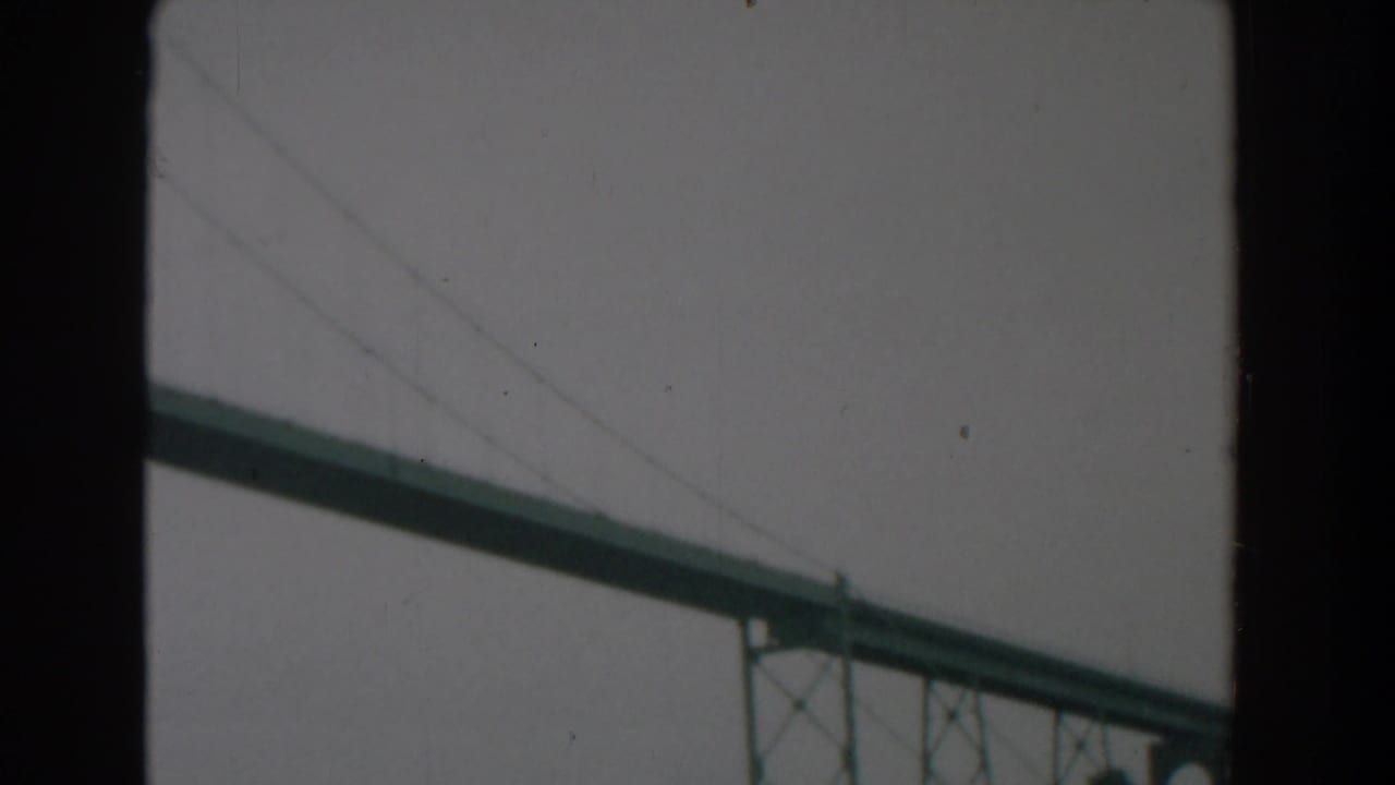 1958 Yorktown, Virginia home-movie frame showing a large green steel bridge behind dark film or window borders.