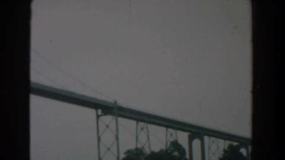 Final 8mm frame of the Yorktown-area bridge, showing the green span, cables, and supports through a dark frame.