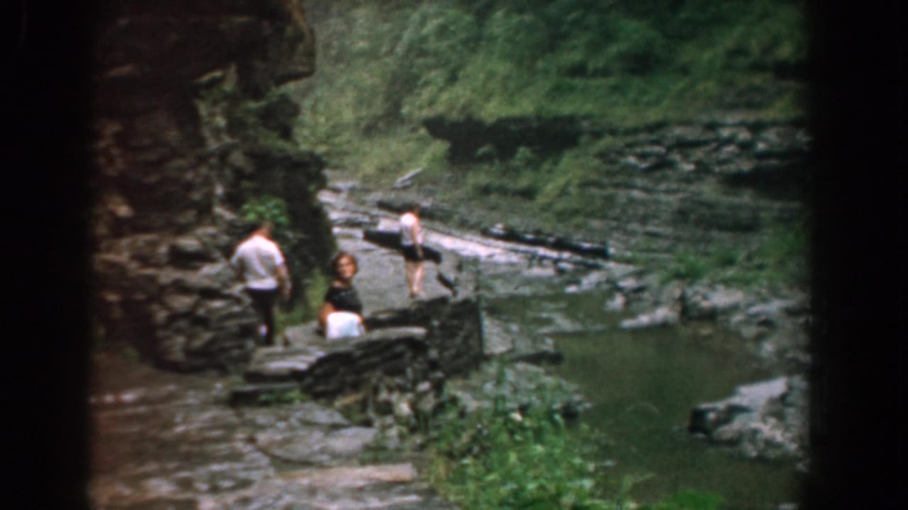 Three walkers continue along the stone path near shallow water.