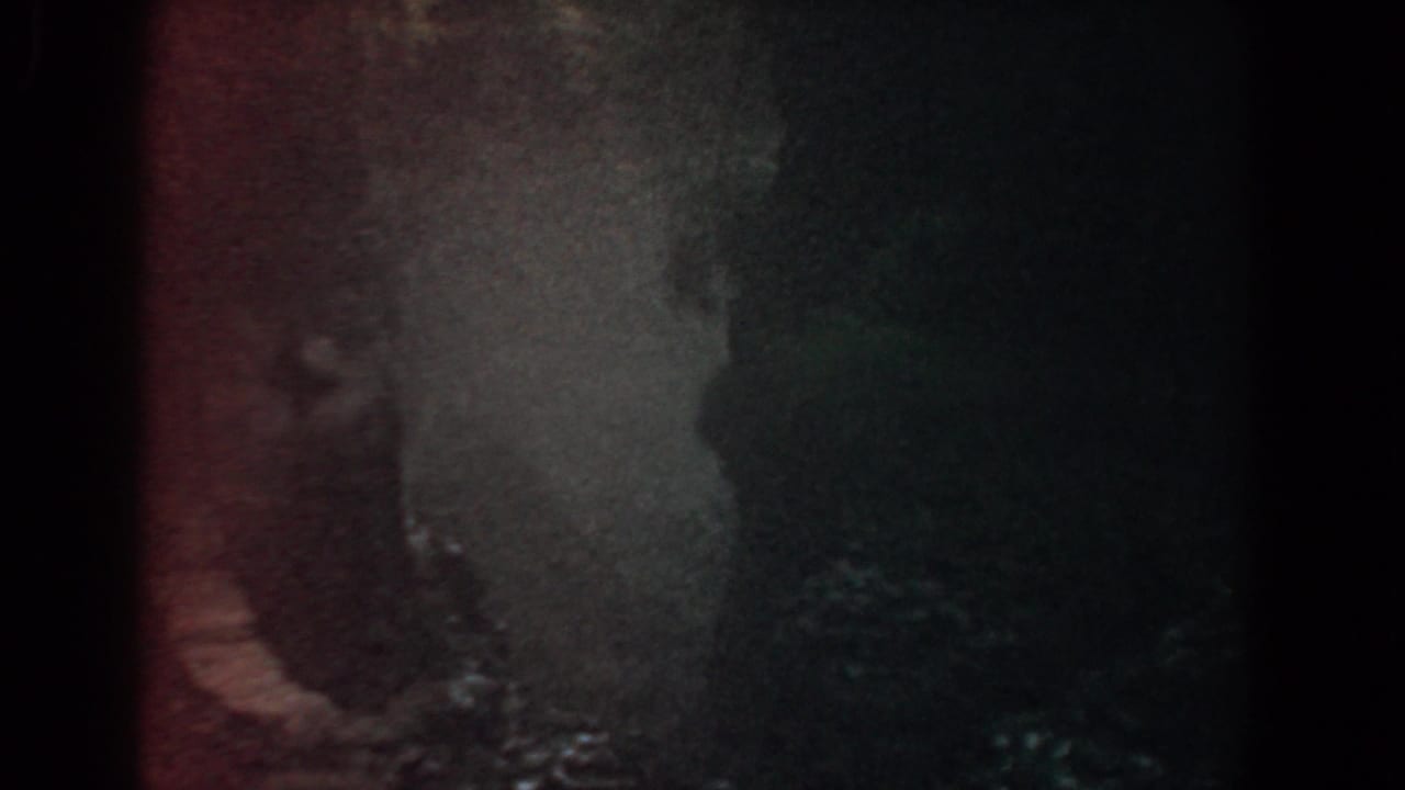 1958 Yorktown 8mm footage showing a close, shadowed view of water moving across dark rock.