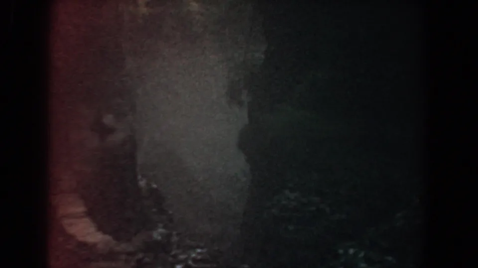 1958 Yorktown 8mm footage showing a close, shadowed view of water moving across dark rock.