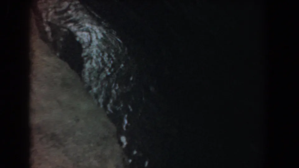 Grainy 8mm frame from Yorktown showing glistening water running between shadowed rock forms.