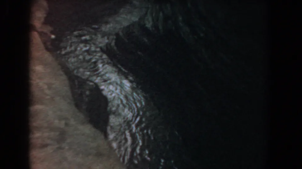 1958 Yorktown close-up of moving water bright against a dark rock edge, with soft 8mm color and grain.