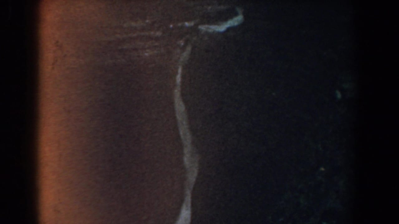 Dark film edge beside a small view of a woman on a sunlit sidewalk.