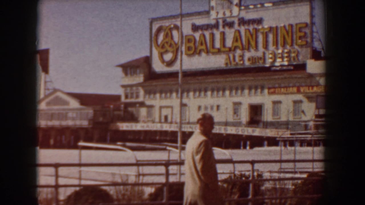 Yorktown boardwalk footage showing a suited man walking beneath a large Ballantine Ale and Beer billboard near pier buildings.