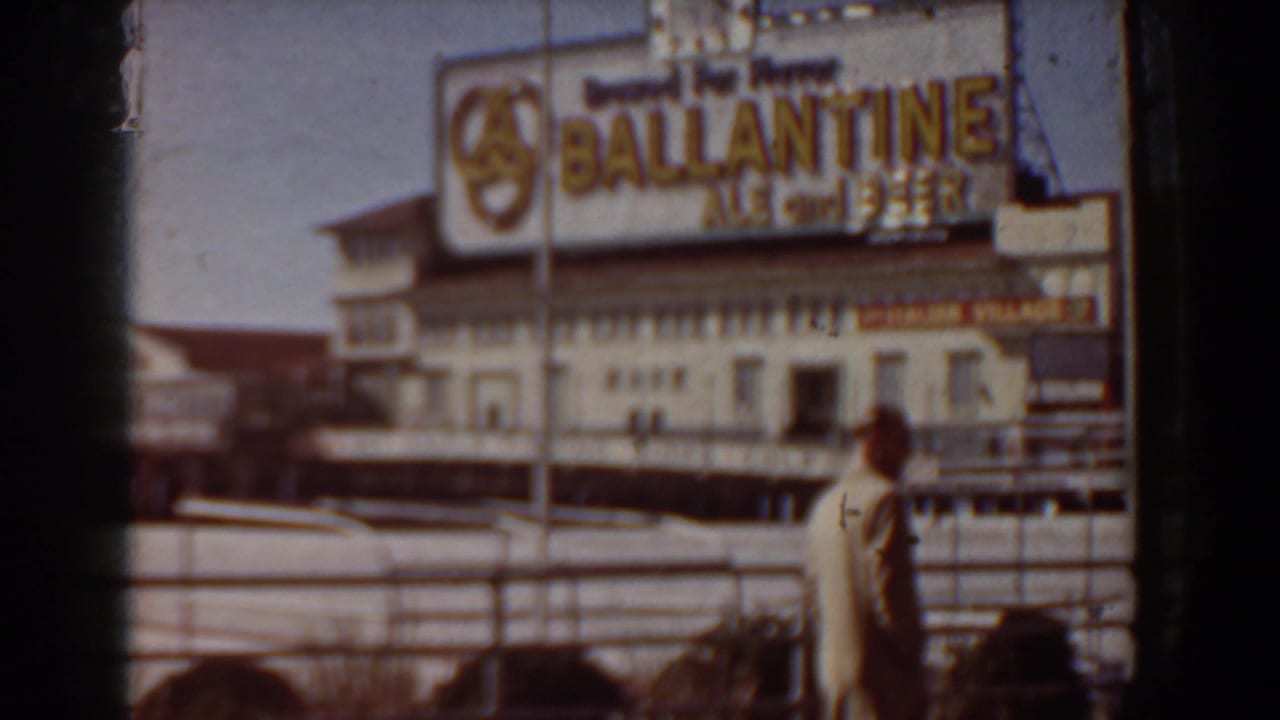 1958 Yorktown, Virginia home-movie frame showing beachside commercial signage, railings, and a person near the sand.