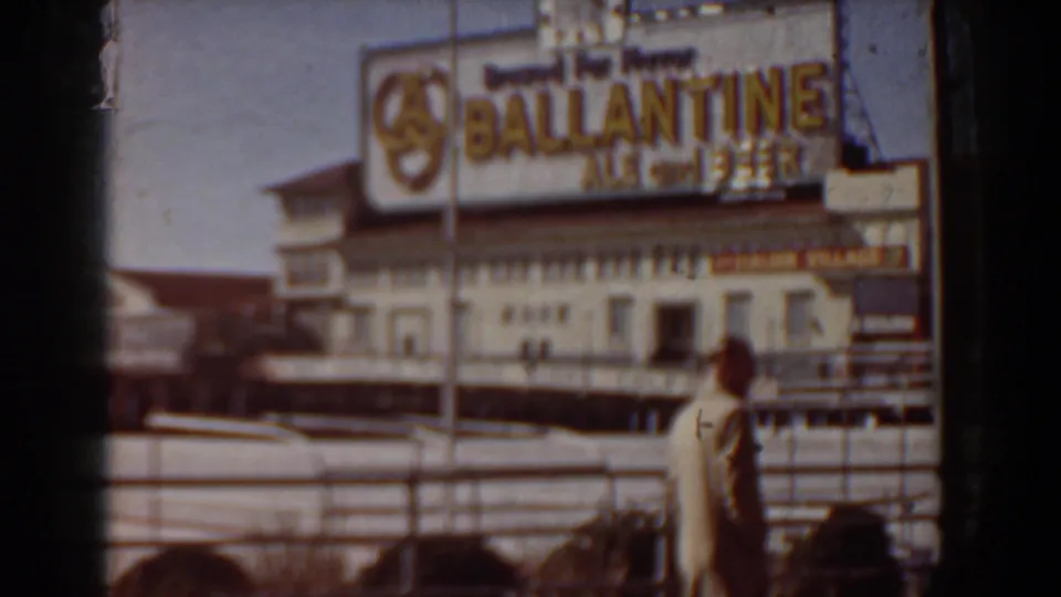 1958 Yorktown, Virginia home-movie frame showing beachside commercial signage, railings, and a person near the sand.