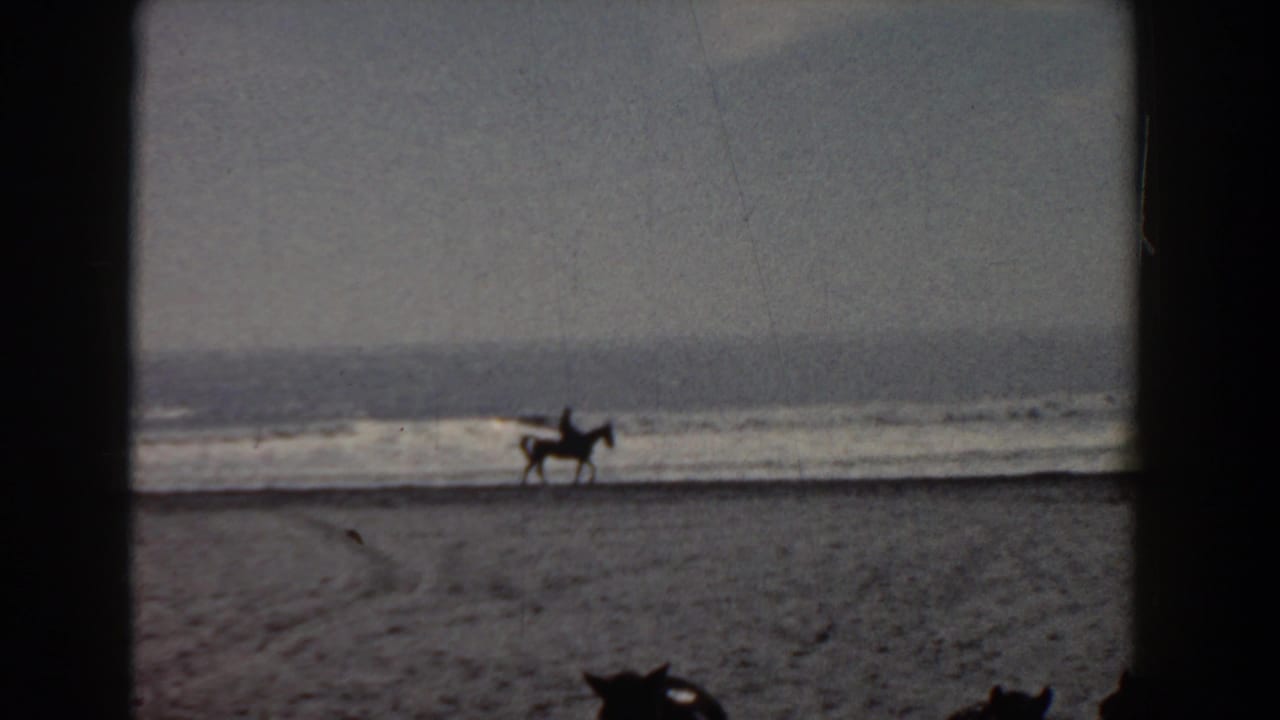 A distant rider on horseback moves along the sandy Yorktown shoreline in grainy 1958 8mm footage.