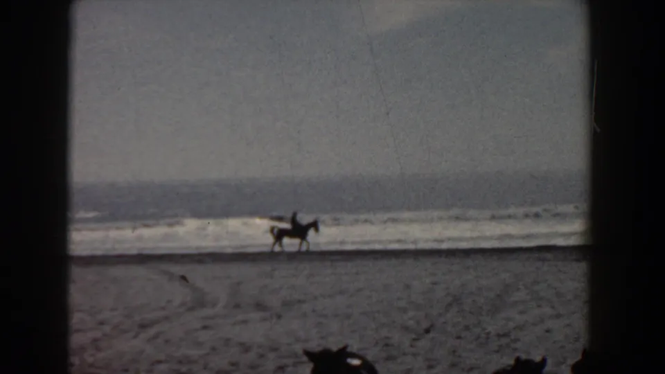 A distant rider on horseback moves along the sandy Yorktown shoreline in grainy 1958 8mm footage.