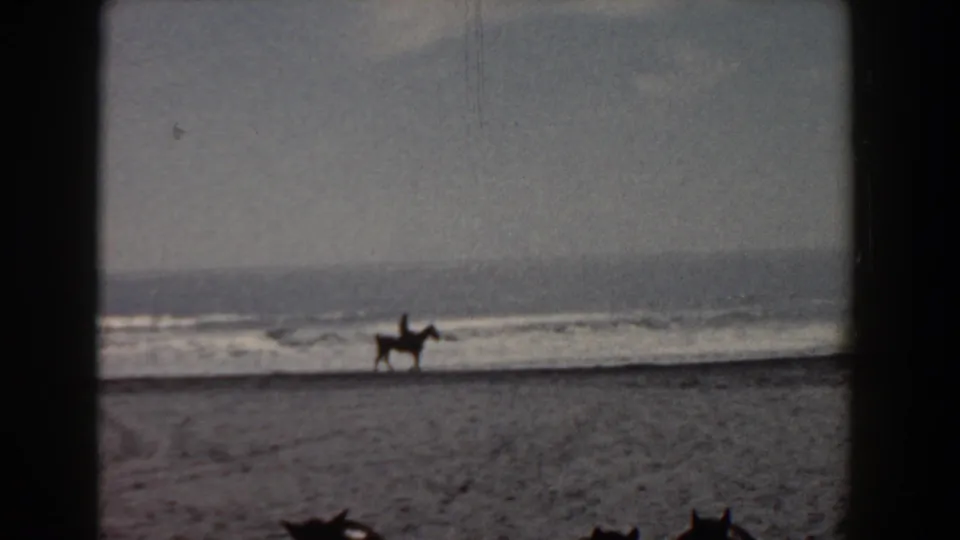 A distant rider on horseback travels along the Yorktown beach shoreline in soft, grainy 8mm color footage.
