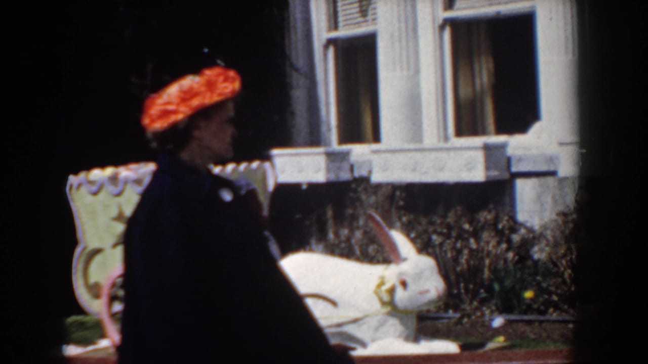 Near the end of the clip, the woman turns into profile while passing the white rabbit statue in the Yorktown garden setting.