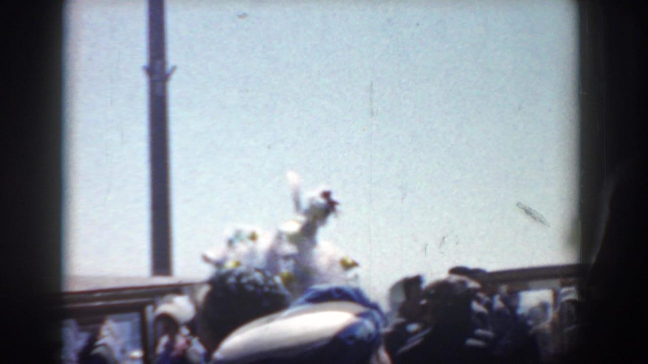 A decorated parade vehicle or float passes near spectators under a bright sky.
