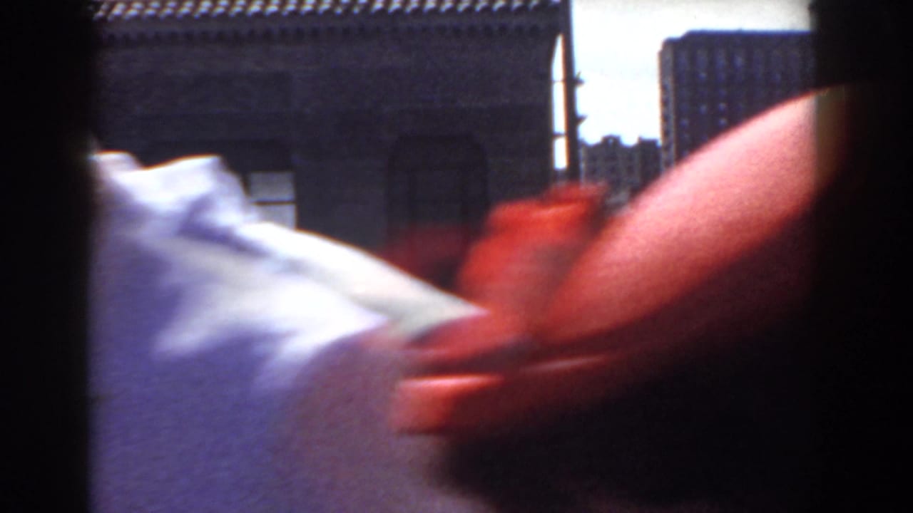 In footage identified as Yorktown, Virginia, 1958, a blurred figure passes close to the camera while pedestrians move along a sunny street.