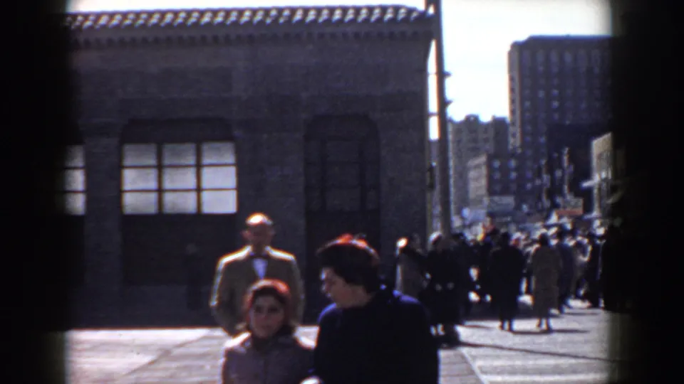 The closing frame shows a 1958 Yorktown street crowd, including women in dark coats and red headwear with a tan-coated man behind them.
