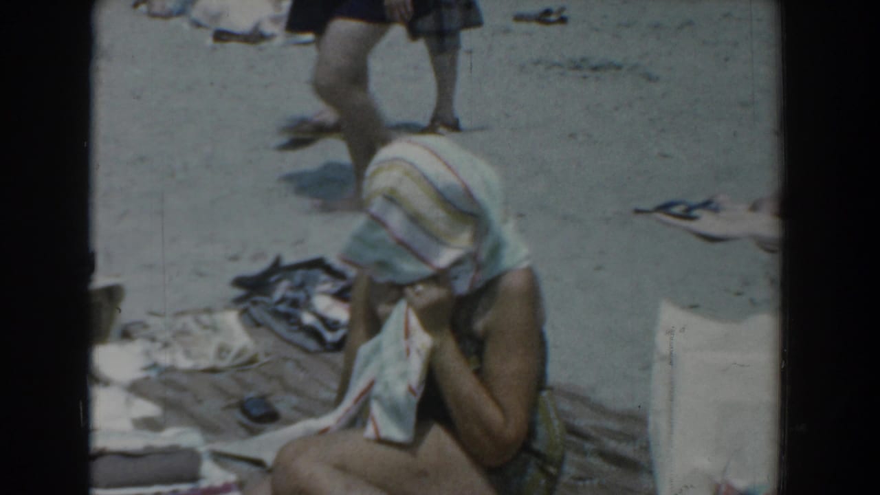 1958 Yorktown beach scene showing a seated woman or older girl drying her head with a striped towel on the sand.